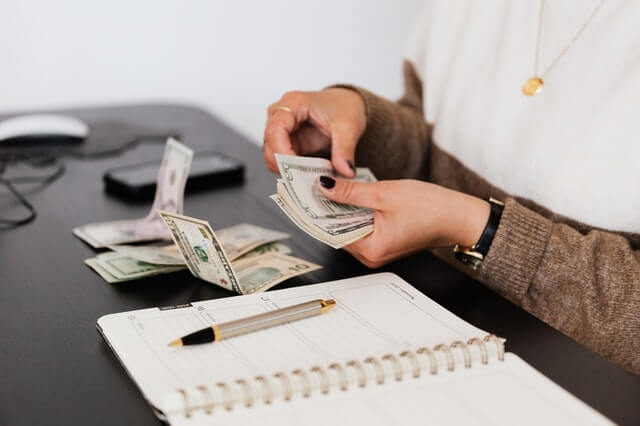 Accueil crop payroll clerk counting money while sitting at table
